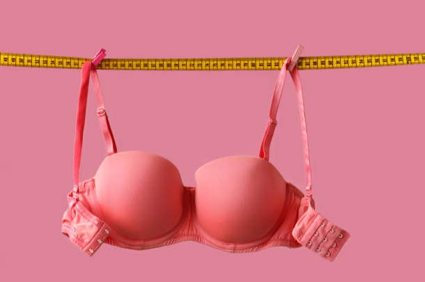 A picture of a bra hanging on measuring tape 